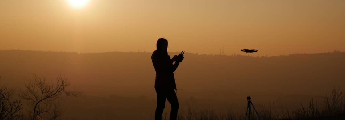 pilote de drone devant couche de soleil