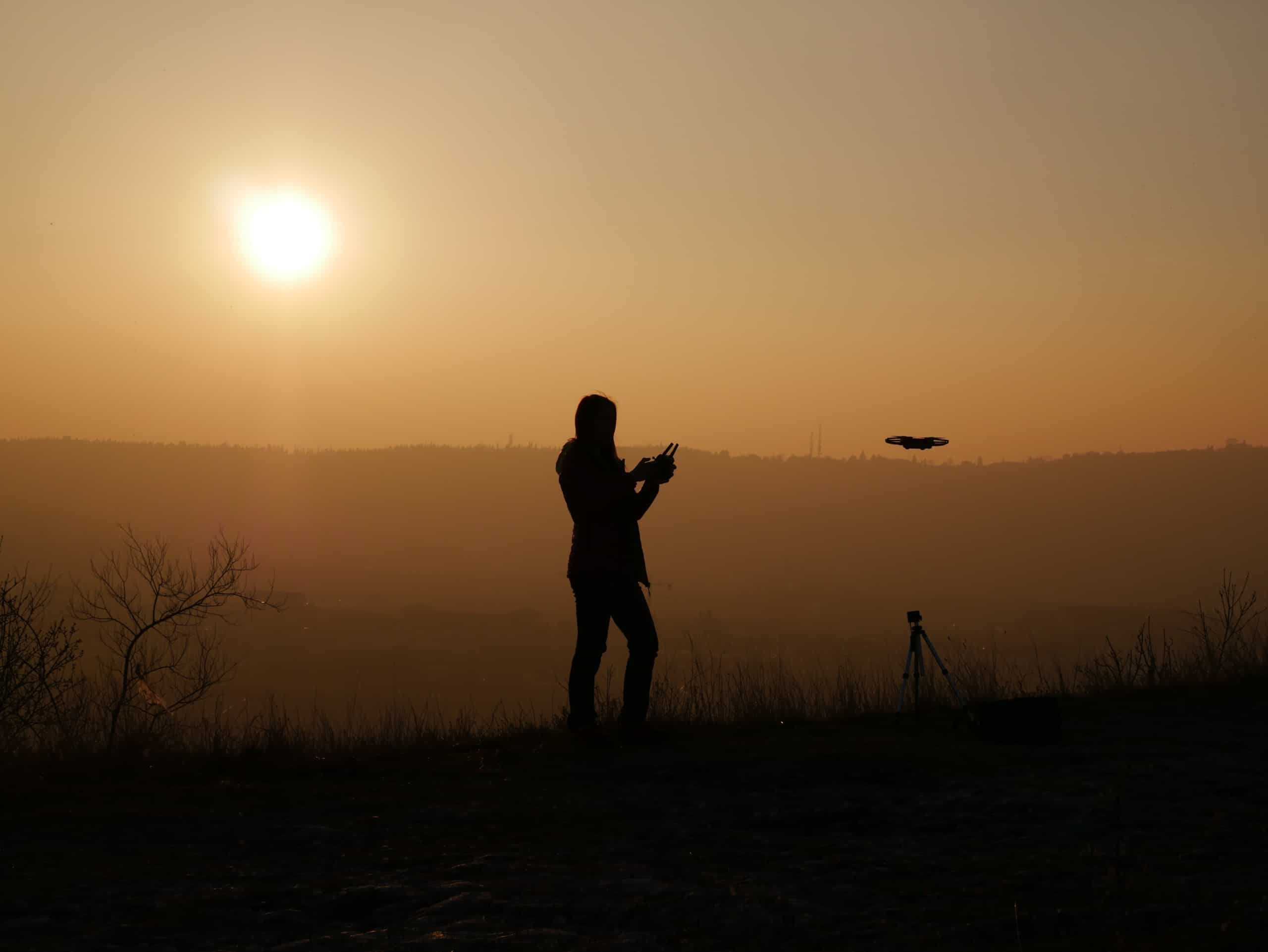 pilote de drone devant couche de soleil